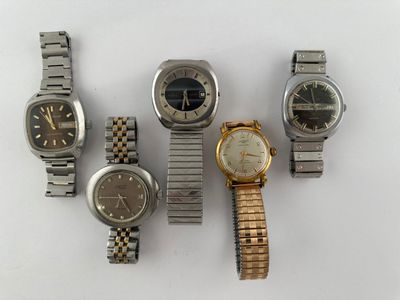 Plusieurs montres différentes sont disposées en rangée sur une surface blanche