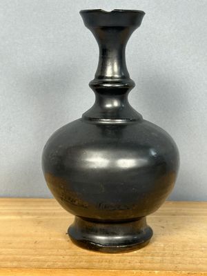 un vase noir posé sur une table en bois