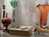 a glass display case with a book, vase, and bird figurines