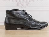 black leather ankle boots with laces on top of a wooden table