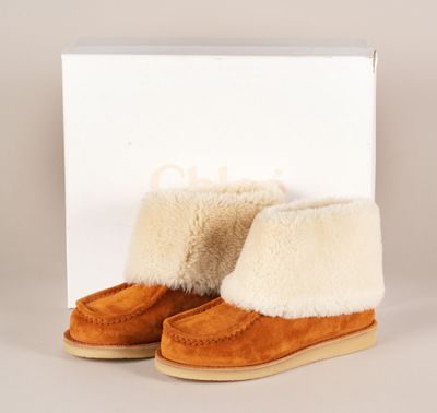 un gros plan sur une paire de bottes en peau de mouton posées sur une surface blanche