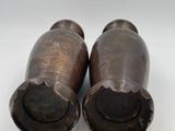 pair of bronze vases on a white surface with a white background