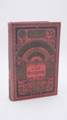 un vieux livre à la couverture rouge posé sur une surface blanche