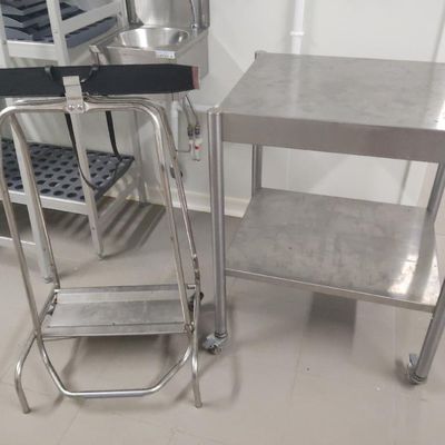 une table en acier inoxydable avec une chaise en métal à côté