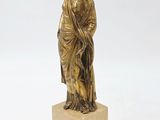 a gold statue of a woman standing on top of a marble block
