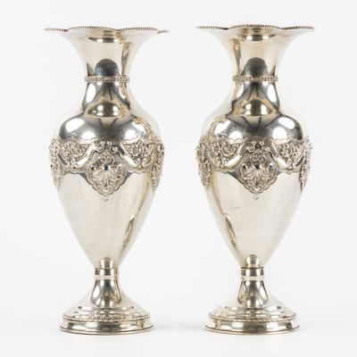 deux vases en argent posés l'un sur l'autre sur une surface blanche