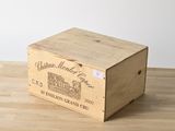 une vieille boîte en bois, sur laquelle est collée une étiquette, posée sur une table en bois