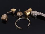 five different pieces of silver and gold on a black surface
