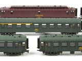 several green and red train cars sitting next to each other on a white surface