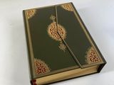 un vieux livre à la couverture verte, rehaussée de dorures sur fond blanc