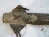 un objet métallique avec un oiseau sur une surface blanche