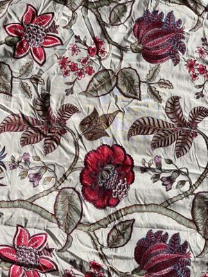 a close up of a quilt with a red flower on it