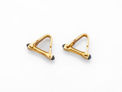 une paire de boucles d'oreilles triangulaires en or sur fond blanc