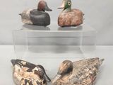 trois canards en bois sont posés sur une vitrine transparente