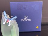 un vase en verre orné d'un papillon, à côté d'une boîte bleue
