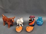 trois petites figurines d'animaux et un chat sur une surface grise