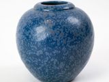 un vase bleu posé sur une surface blanche