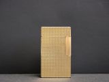 un briquet doré posé sur une table près d'un mur noir