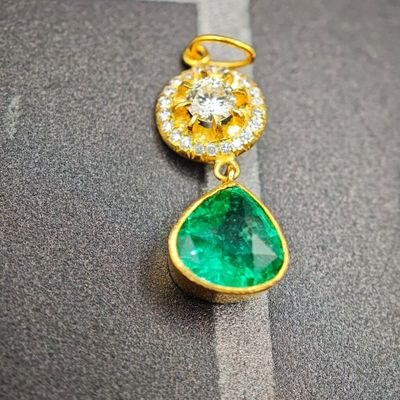 une photo d'une paire de boucles d'oreilles en émeraude et diamant posées sur un morceau de tissu