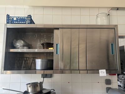 une armoire en acier inoxydable dans une cuisine, avec des casseroles et des poêles posées sur le plan de travail