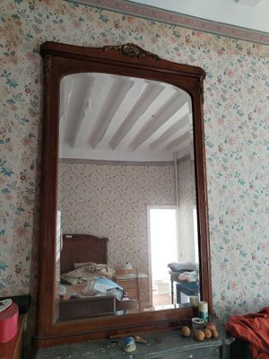 a mirror on a dresser in a room with a floral wallpapered wall