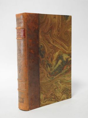 an old book sitting on top of a white table next to a white wall