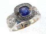 gros plan d'une bague avec une pierre bleue entourée de diamants