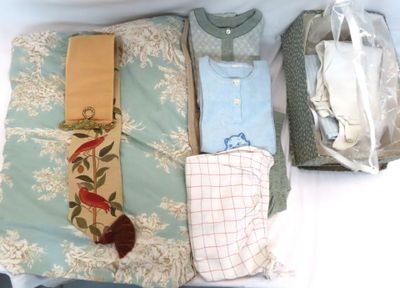 Plusieurs vêtements sont rangés dans une valise posée sur un lit