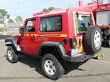 a red jeep parked in a parking lot with a firetruck in the background