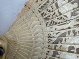 a close up of a white lace fan on a table