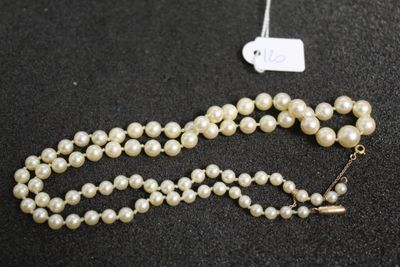 a close up of a necklace with pearls on a black surface
