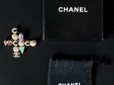 a chanel cross brooch with pink and green stones and a black velvet bag