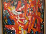 peinture abstraite représentant des formes rouges, orange, bleues et blanches, dans un cadre en bois