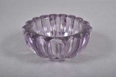 un bol en verre violet posé sur une table blanche, sur fond blanc
