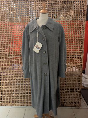 grey coat on a mannequin stand in front of a woven screen