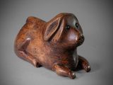 wooden sculpture of a pig laying down on a gray surface