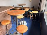 des tables et des tabourets dans une pièce au sol bleu et dotée d'une fenêtre