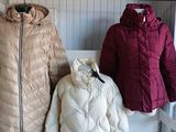 two jackets and a coat are sitting on a bench in front of a wall
