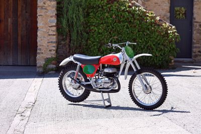 a red and green dirt bike parked in front of a stone building