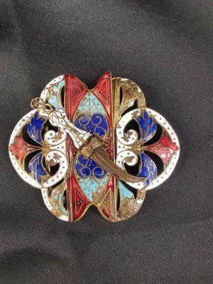 une image représentant une broche avec une épée au centre