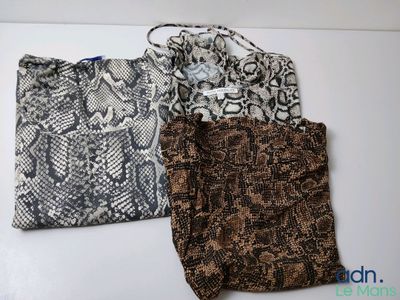 three bags are lined up on a white surface, one is brown and the other is black and white