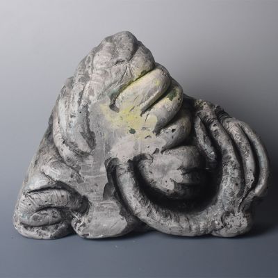 une sculpture représentant une personne assise sur un rocher, la tête entre les mains