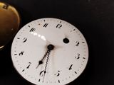 a clock that is sitting on a table next to a pocket watch