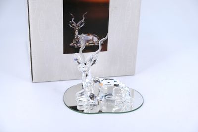 a glass deer figurine on a plate with a picture in the background
