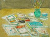 un tableau posé sur une table, avec un pot de peinture et des feuilles de papier