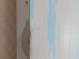 peeling paint on the wall of a bathroom with a toilet in the corner