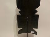 black sculpture of a man on a pedestal with a white wall behind it