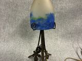 an old fashioned lamp with a blue and white shade on a metal stand