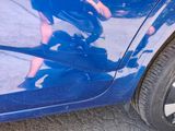 a reflection of a man riding a skateboard on the side of a blue car