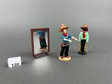 deux figurines représentant un homme et une femme debout devant un miroir